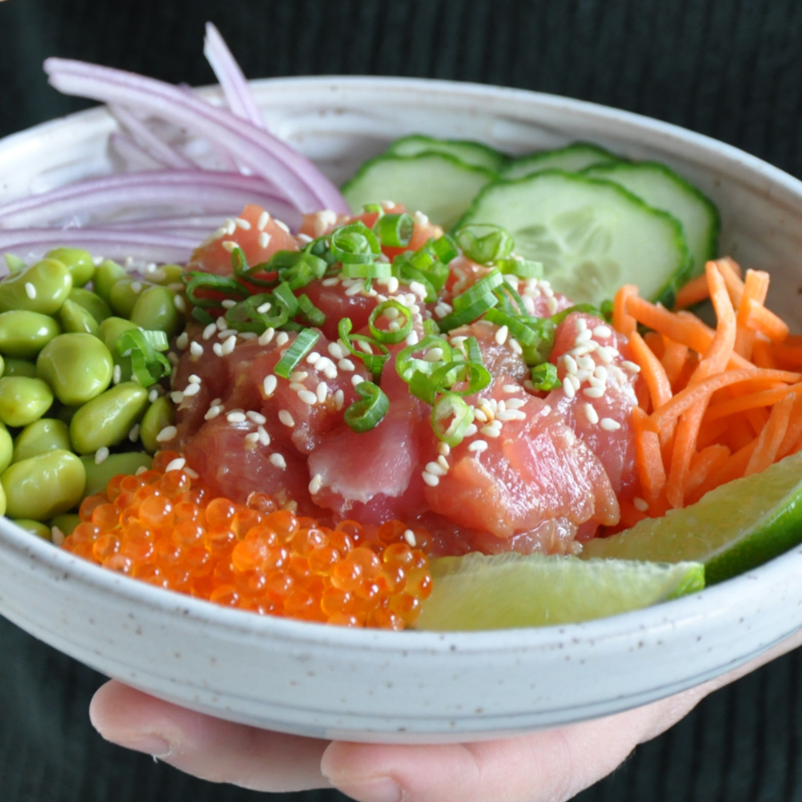 Bowl of poke with various ingredients held by a person